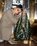 Person holding a green handbag with decorative studs in an indoor setting