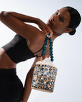 Woman holding a decorative handbag with beads against a white background