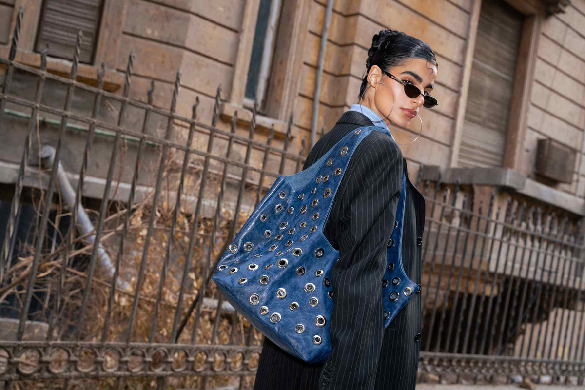 Person wearing a blue studded bag in an urban setting