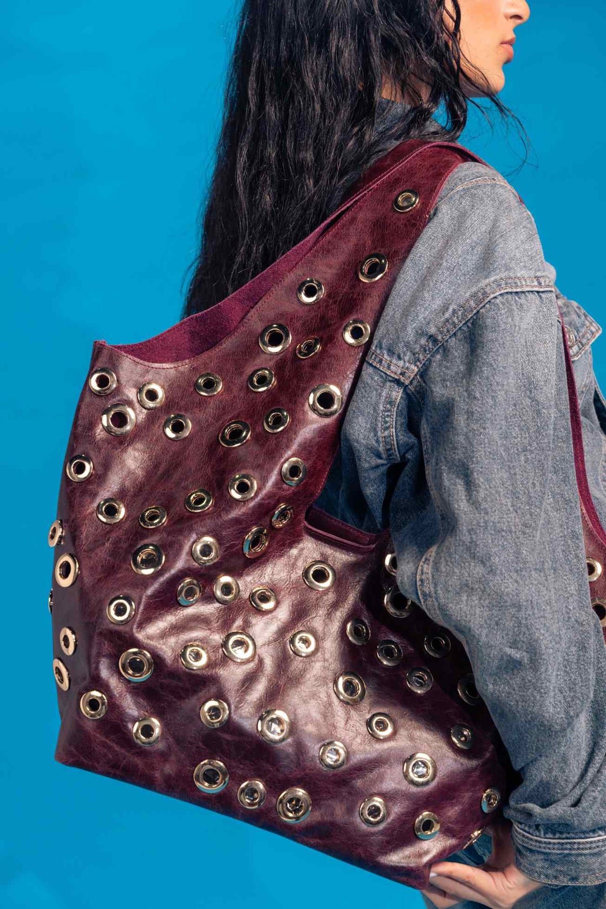 Person wearing a purple backpack with grommets against a blue background